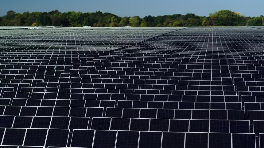 Aerial fly over rows of solar panels on solar farm