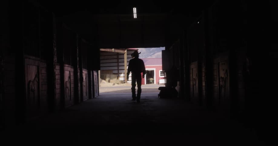 A man walking inside horse stalls