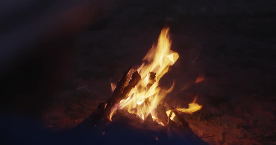 Man observing a small campfire on the sand
