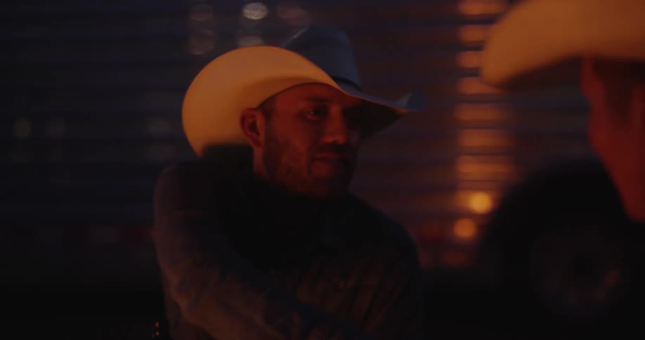 Two men in cowboy hats are shaking hands with each other