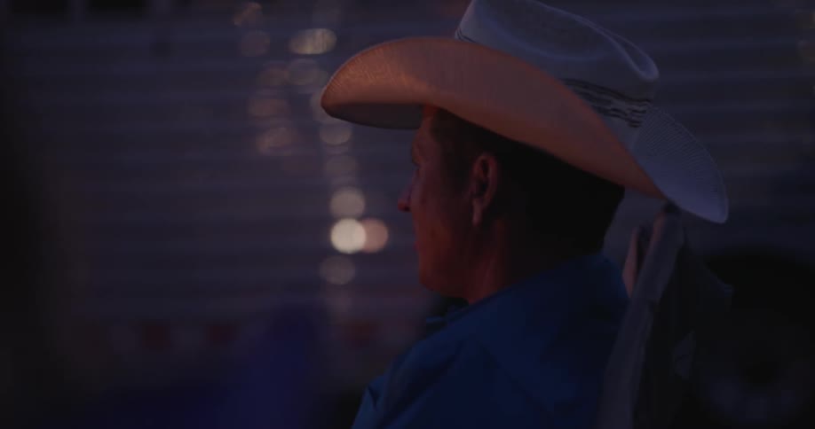 A man wearing a hat sitting in a chair drinking coffee