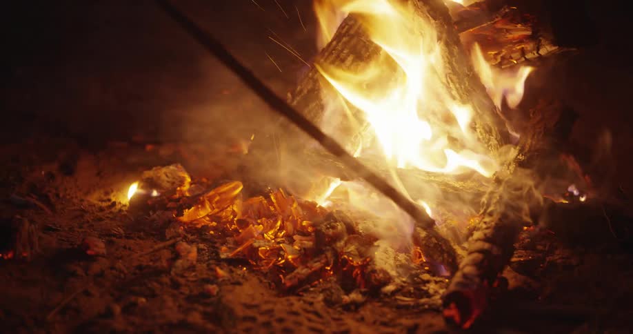 Close up of a campfire being stoked at night