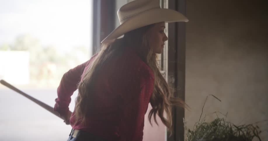 Woman opening the ranch door and bringing hay to the horse