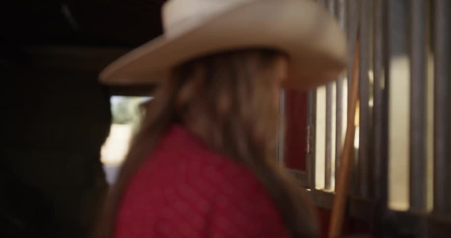 Portrait of a woman closing the gate while the horse is eating in the ranch