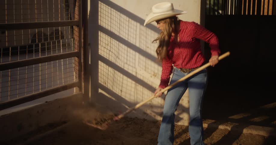 Lady packs some sand in a ranch house with a wooden shovel during the day