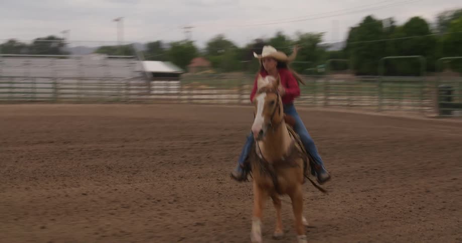 Cowgirl riding a horse in a corral