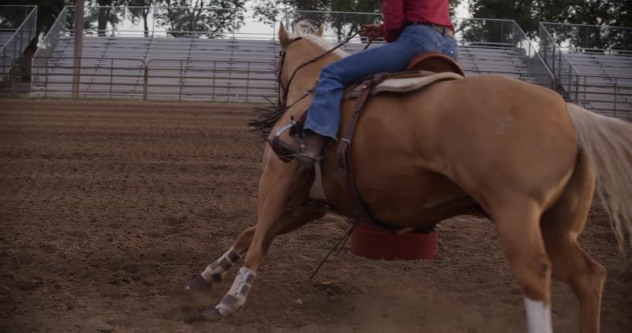 A person riding a horse on a ranch and riding over an obstacle