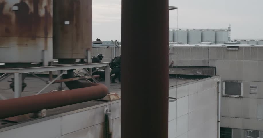 Two police officers on a building terrace carrying firearms