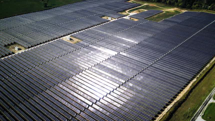 Aerial view of a solar farm with sunlight reflecting off the panels