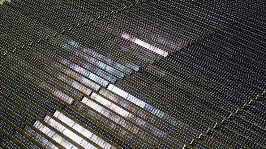 Golden hour aerial view off solar farm with sunset colors reflecting off of the panels