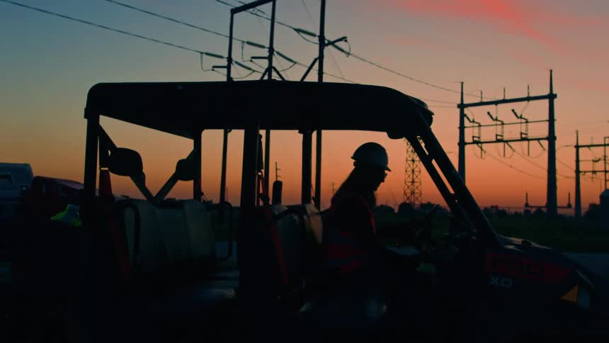 Sunrise silhouette of a female construction worker starting the day in work vehicle