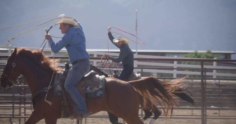Cowboys spinning lassos over their heads while riding in the rodeo