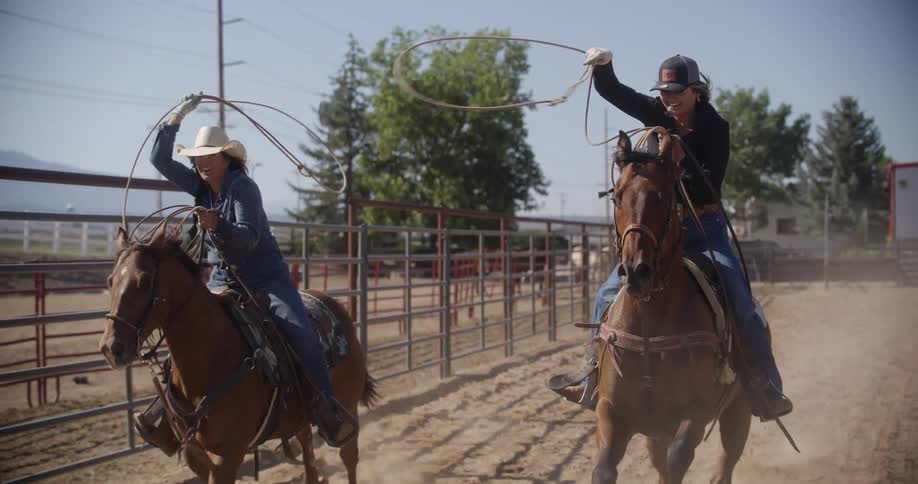 Two women swing lassos on horseback