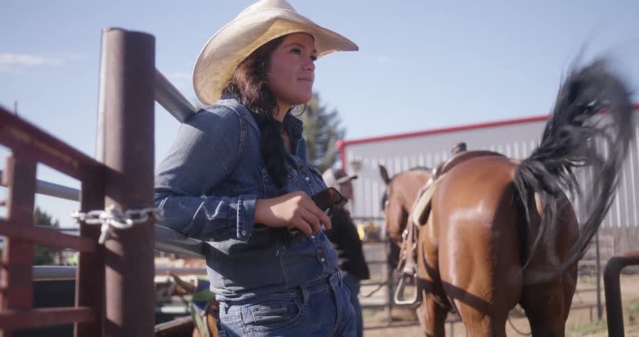 A woman leaning against an iron railing near a horse