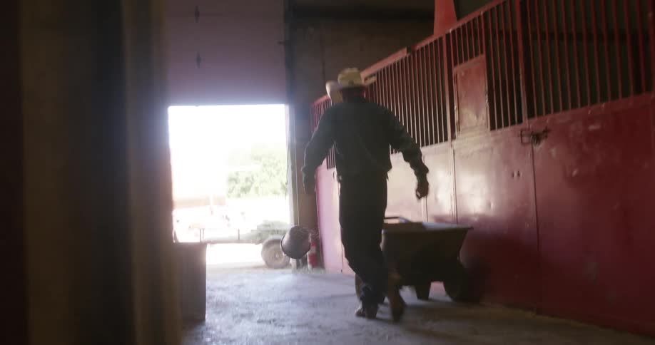 Man walking inside a ranch and kicking a bucket in frustration