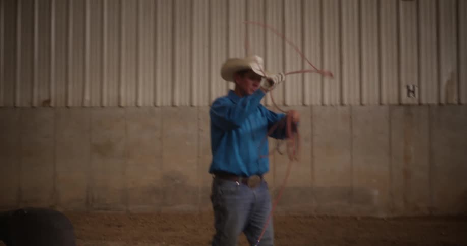 A cowboy with a rope in his hands starts to twirl it