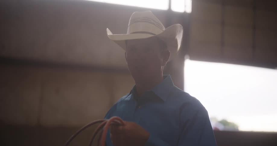 A man in a bowboy hat is spinning a lasso rope