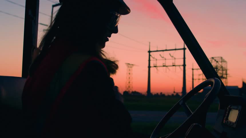 Silhouette of a female construction worker boarding a truck at sunset