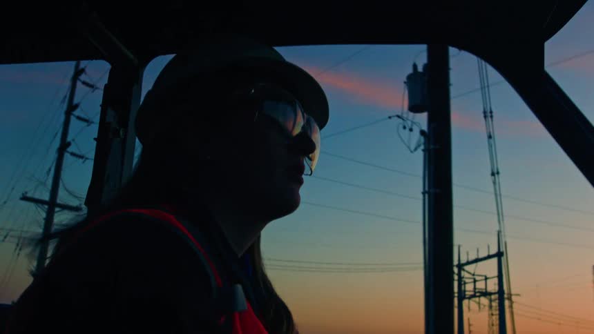 Portrait of a female construction worker driving vehicle in the early morning with pink sky