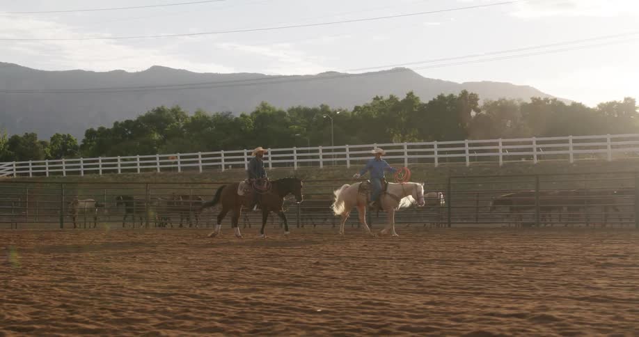 Two cowboys ride horseback on the ranch