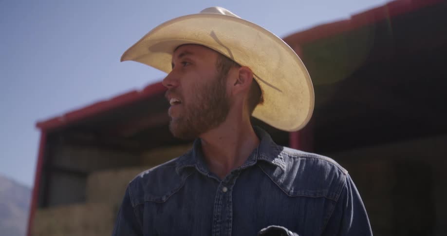 A man wearing a cowboy hat standing under the sun