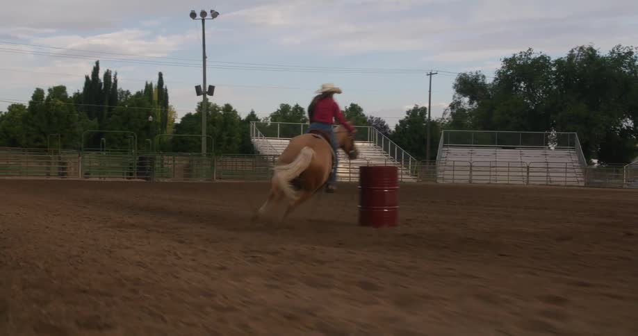 A woman running on a horse in a dirt arena