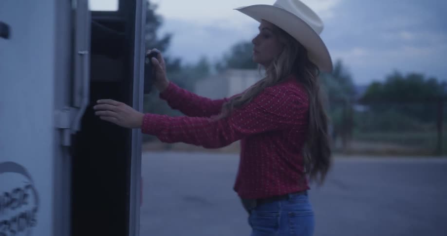 A woman with cowboy hat is closing a door