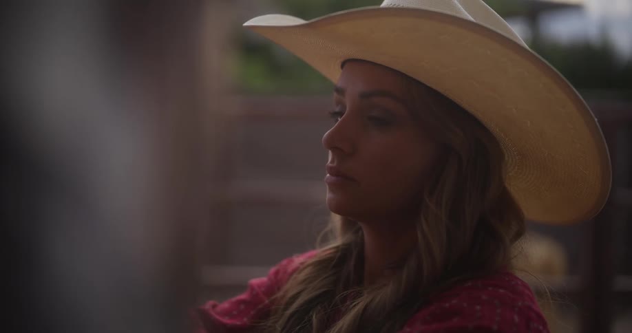 Am woman caring for a horse while wearing a cowboy hat