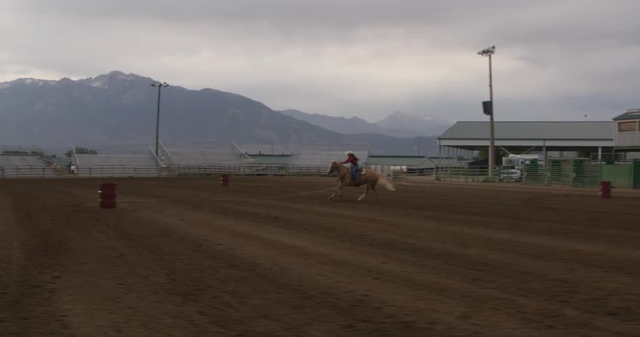 A woman races her horse around barrels in the arena