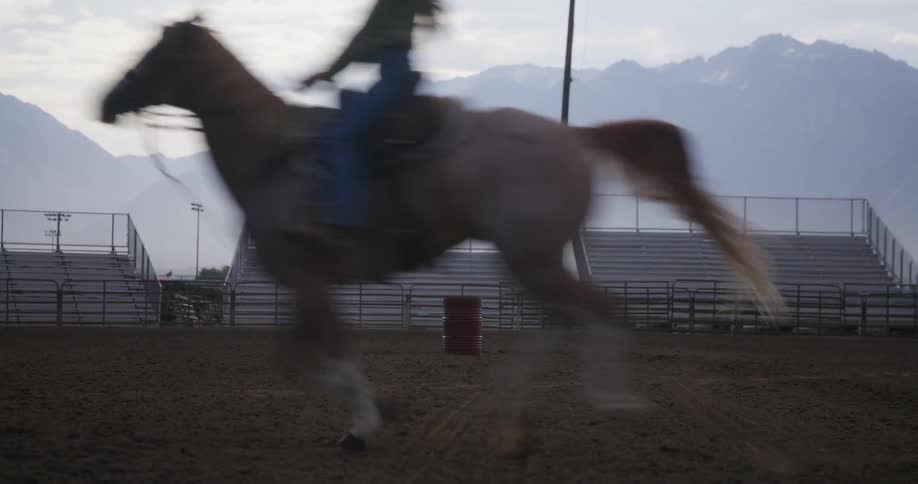 A woman is horseback riding on a dirt covered ground