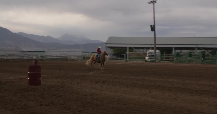 Person riding a horse on a sandy field at midday