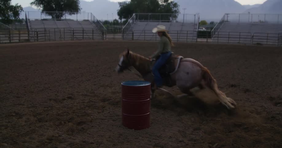 A woman on a horse running in an arena