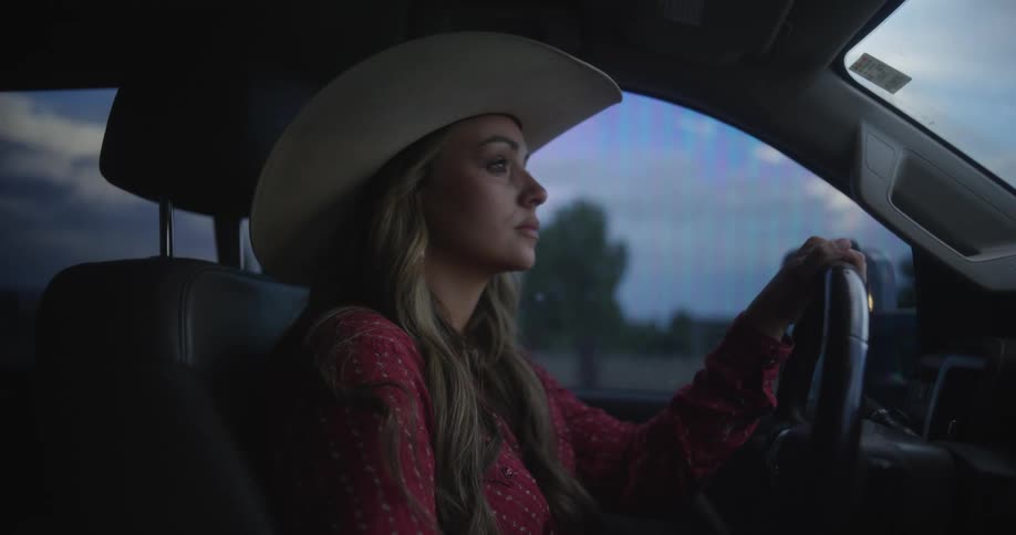 A woman is driving a truck and looks around as traffic passes