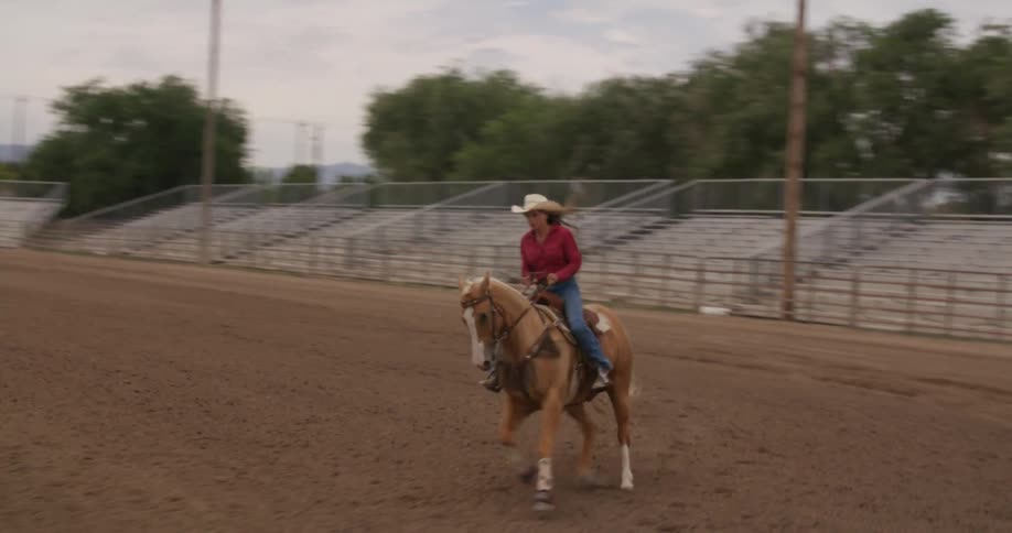 Lady riding a horse on a sandy field during the day