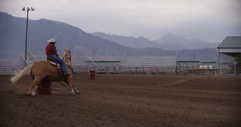 A woman races her horses around the barrels