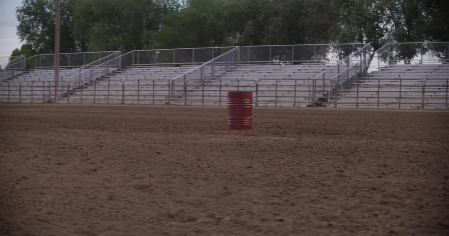 Panorama of red metal barrels in the middle of the sand inside a rodeo arena