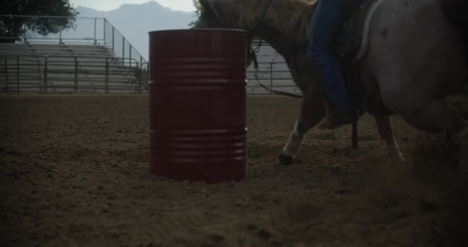 Horse performing a steering maneuver around a barrel in the middle of a rodeo arena