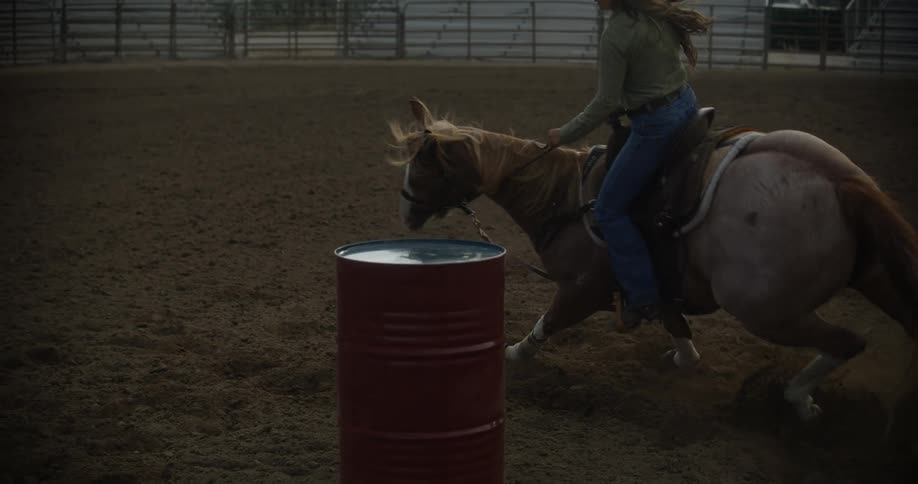 Woman on top of a horse performing equestrian maneuvers with changes of direction in a sandfilled ranch