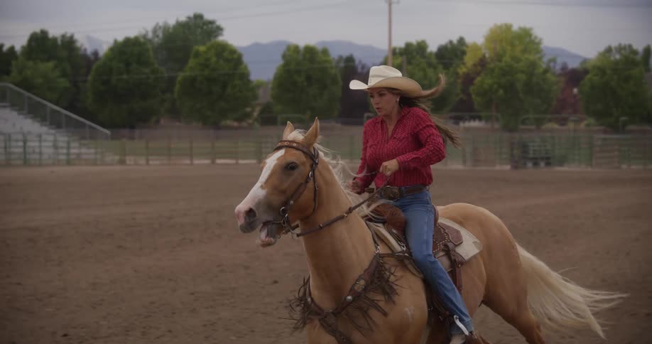 A woman riding a horse running in the arena