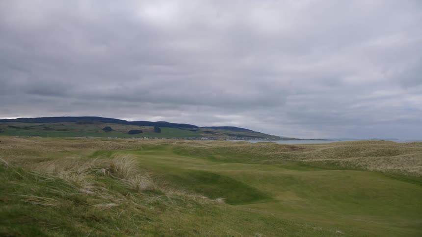 A landscape of a grasfield with some hills in the horizon