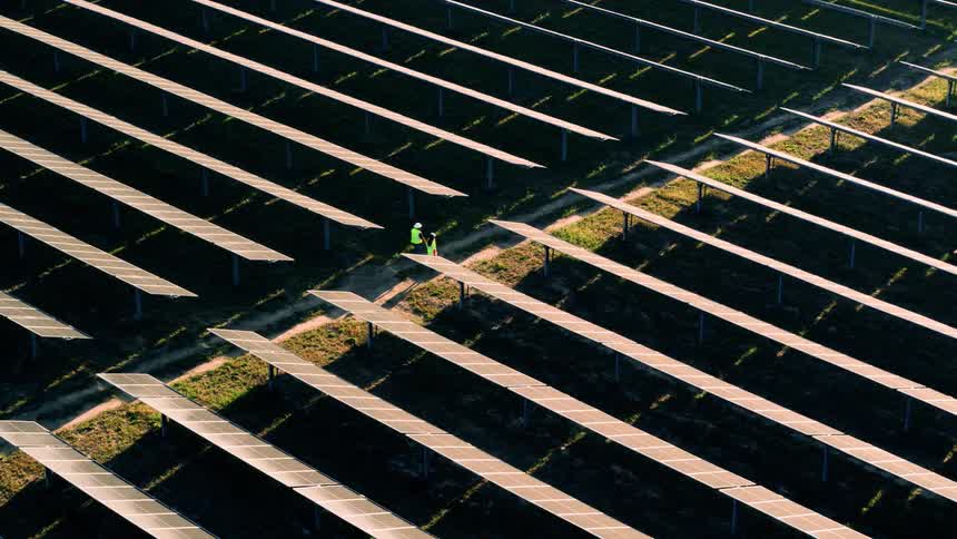 Aerial view of workers walking among solar panels on a solar farm