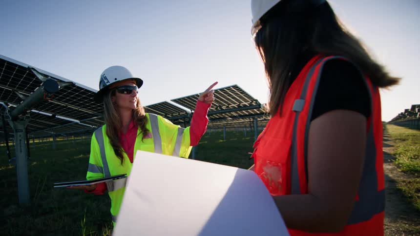 Two female engineers inspecting solar panel field