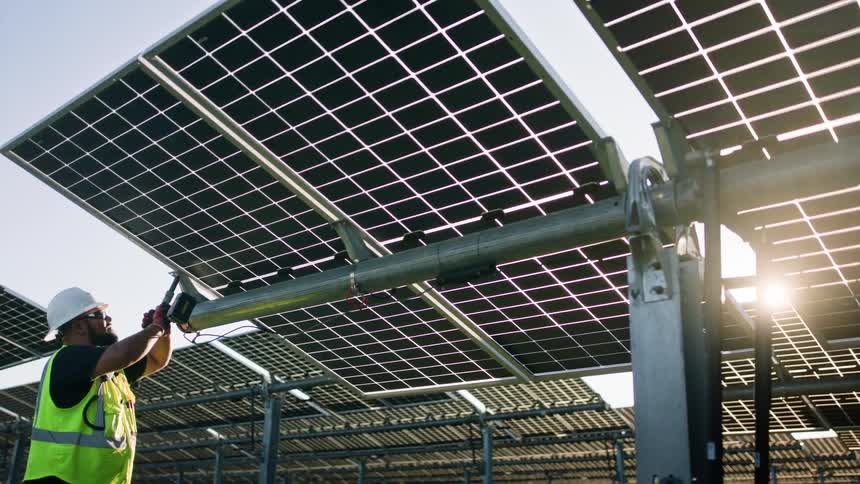 Construction worker screwing a solar panel onto a surface