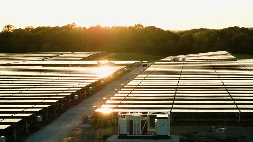 Panorama of a power station with solar panels at golden hour with light reflecting off the cells