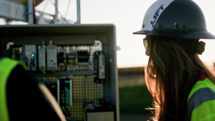 Two construction workers doing maintenance on an electrical breaker station