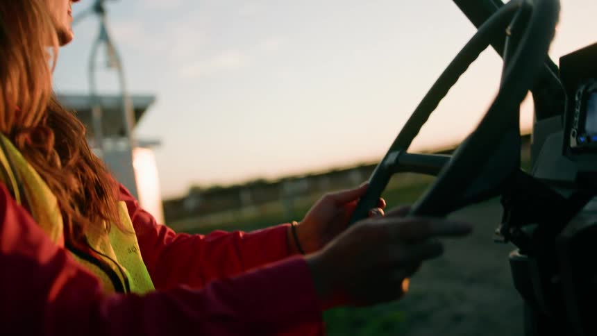 A female putting on hard hat and safety vest while driving a truck