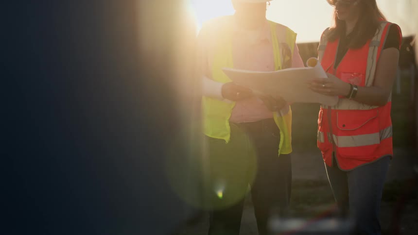 Female construction worker and supervisor at sunset