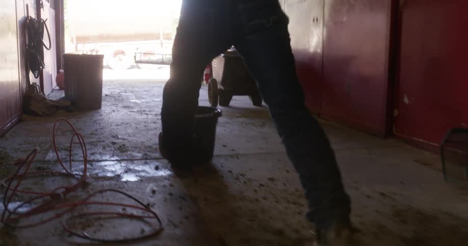 Angry cowboy walking out of the ranch and kicking a bucket