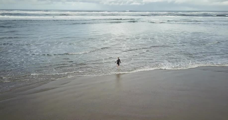 A person is running into the water of a beach