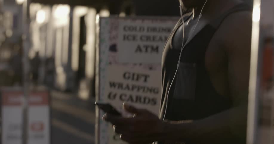 A man is standing outside listening to music on his phone